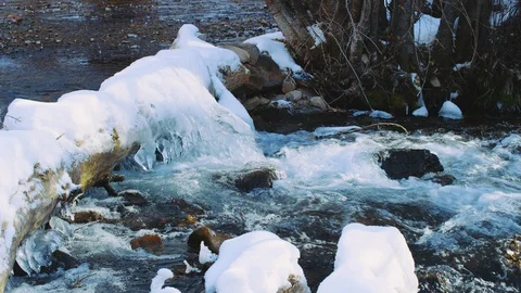 Freezing cold river covered in ice and snow in slow motion dolly move upriver Video stock 129416837