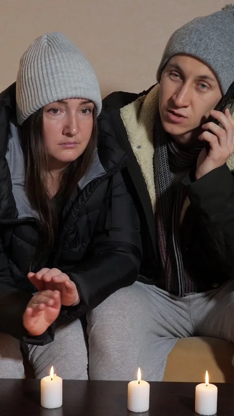 Freezing couple in winter clothes warming hands over candles during a power Stock-Footage 341678069