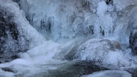 A freezing mountain stream and snow-covered boulders Stock Footage 262610897