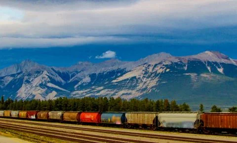 Freight container train in Jasper with snowy mountains on the back. Alberta.  Stock Photos