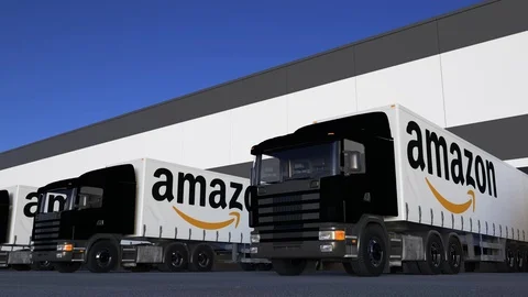 Freight semi trucks with Amazon.com logo loading or unloading at warehouse dock Stock Footage 78134120