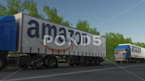 Freight semi trucks with Amazon.com logo driving along forest road. Editorial 3D Stock Photos