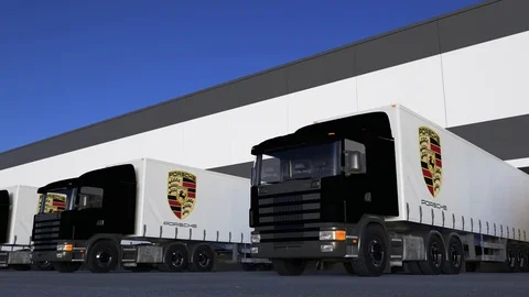 Freight semi trucks with Porsche logo loading or unloading at warehouse dock Stock Footage