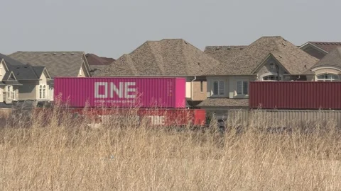 Freight train and shipping containers in residential area with homes close by Vídeo Stock 151667858