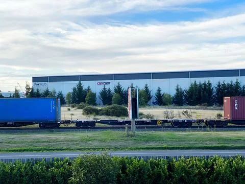 Freight train with blue and red cargo containers passing industrial warehou.. Stock Photos