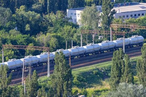 Freight train carrying cargo moves through a green landscape with trees and.. Fotos de archivo
