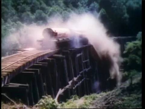 Freight train carrying logs falling off collapsing bridge Stock Footage 260257690