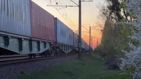 Freight Train Carrying Shipping Containers Moving Along Railway at Sunset Stock Footage 333430626