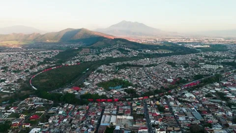 Freight train crossing the city of Tepic with the sanganguey volcano in the Stock Footage 332132271