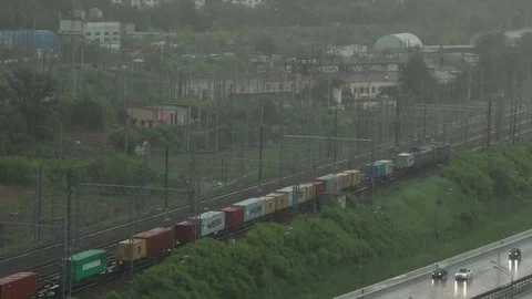 Freight train crossing industrial zone during heavy rain. Stock Footage