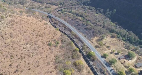 Freight train crossing under road and small river rounding corner aerial shot Stock Footage 95913519
