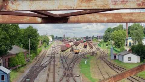 Freight train depot and railway tracks framed through steel bridge structure in Stock Footage 344356610