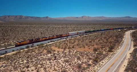 Freight train driving through the flat Californian dessert Video stock 237953665