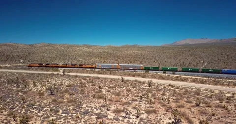Freight train driving through the flat Californian dessert Stock Footage 237953744