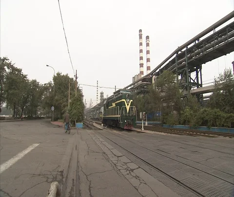 Freight train engine next to pipes leading from old coal burning power plant Stock Footage 86744720