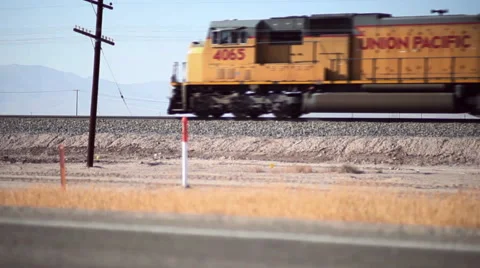 A Freight train enters frame moving fast through the desert. Stock Footage 58197319