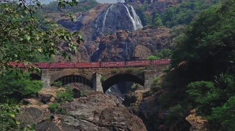 Freight train goes by rail in the mountains near waterfall Stock Footage 59797066