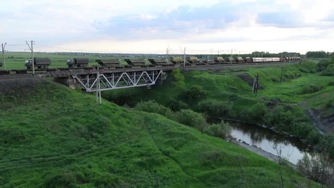 Freight train goes through the railway bridge, summer evening Stock Footage 76513912