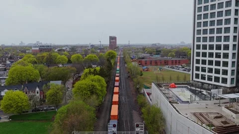 Freight train with intermodal containers moving on railway tracks through urban Stock Footage 334697046