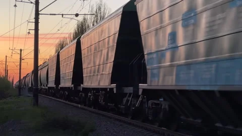 Freight Train Moving Along Railroad Track at Sunset | Long Cargo Train Stock Footage 333725211