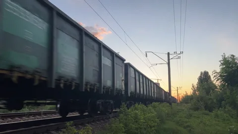 Freight Train Moving Fast on Railway Track at Sunset | Cargo Wagons Passing Stock Footage 340919903