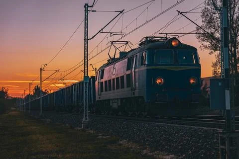 Freight train moving at sunset in warm golden tones Stock Photos