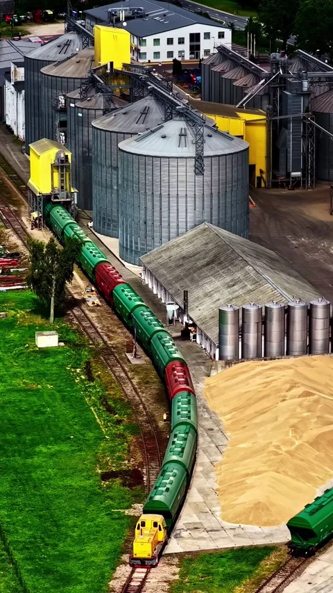 Freight Train Navigates Grain Storage Facility with Vibrant Green and Red Cars Stock Footage 336101764
