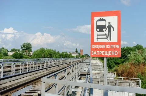 A freight train passes over the bridge. Signage Walking on the tracks is pr.. Stock Photos