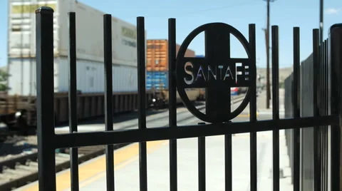 A freight train passes a Santa Fe iron gate in a rail yard railroad Stock Footage 52579057