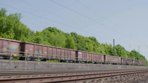 Freight Train Passing by Lush Green Trees Along Railway Tracks on Sunny Day Stock Footage 334054892