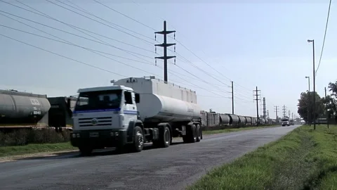 Freight Train Passing Parallel to Trucks on Rural Road, Logistics Corridor Stock Footage 145501439