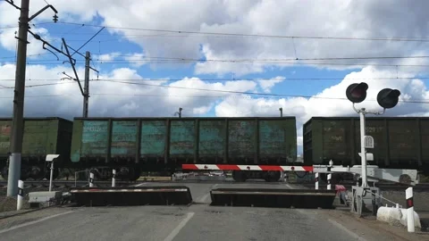 Freight train passing by a railway crossing in summer against a blue sky 库存影片 160265031