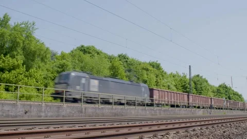 Freight Train Passing Through Green Landscape Along Railway Tracks on a Sunny Da Stock Footage 334054877