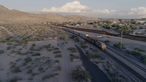 Freight train passing the U.S. Mexico border wall at sunset, El Paso, Texas Stock Footage 127726323