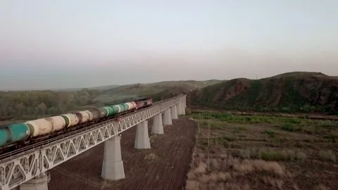 Freight train rides with a locomotive with oil barrels across the bridge. aerial Stock Footage 101650714