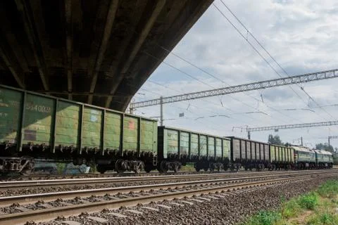 Freight train rides by rail under the road bridge Stock Photos