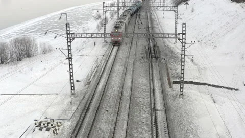 A freight train rides on snow-covered rails along the river. Stock Footage