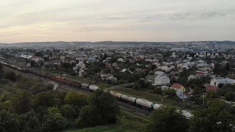 Freight train rolls across rural landscape among private houses, aerial view. Video stock 107391631