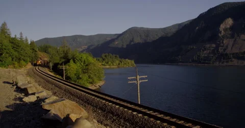 A freight train rumbles along the Washington State side of the Columbia River Stock Footage 59859091