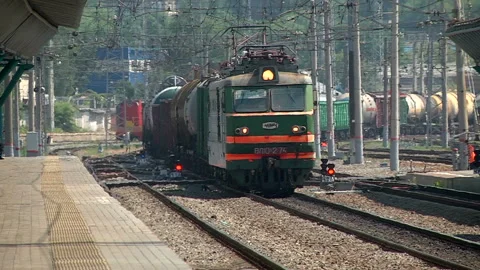 A freight train runs along the platform of the station Stock Footage 98116679
