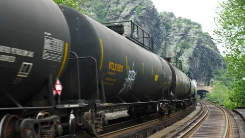 Freight train with tanker carriages winding along a mountain rail track Video stock 150476232
