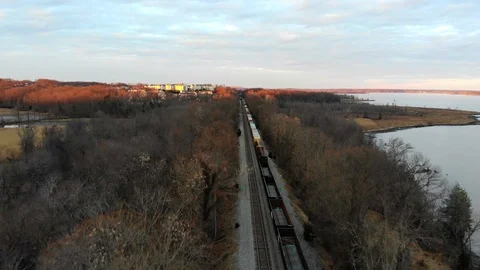 Freight Train through the trees along river at sunset 動画素材 104011506