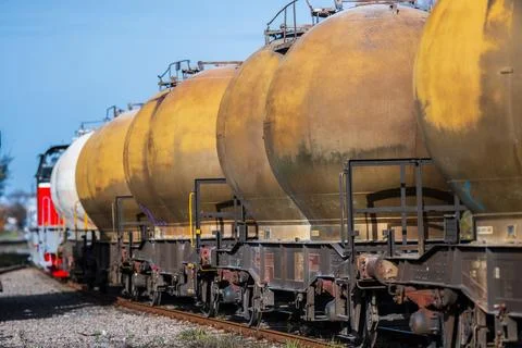 Freight train transporting tanks through an industrial area. Stock Photos