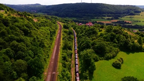 Freight Train Traveling Through Lush Green Valley Beside Parallel Railway Stock Footage 313191767