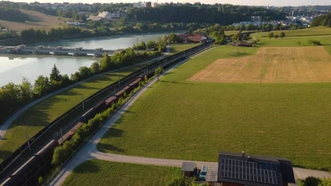 Freight train travelling along the river Inn past a hydropower plant Stock Footage 341467344