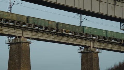 Freight train wagons move along a two-column railway bridge Видео 123410204
