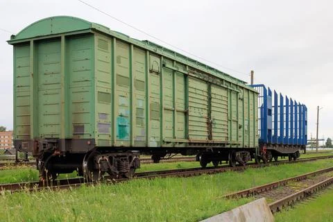 Freight train wagons on a railway track. Green cargo boxcar is coupled with.. Stock Photos
