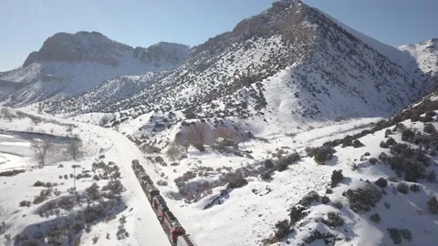 Freight train in winter mountains next to river Video stock 166128533