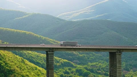 Freight transport lorry on elevated mountain road surrounded by lush green Stock Footage 310361501