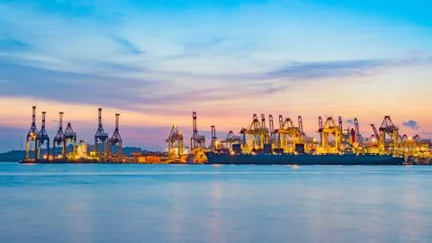 Freighter ship loading cargo at loading dock on twilight time. Stock Photos